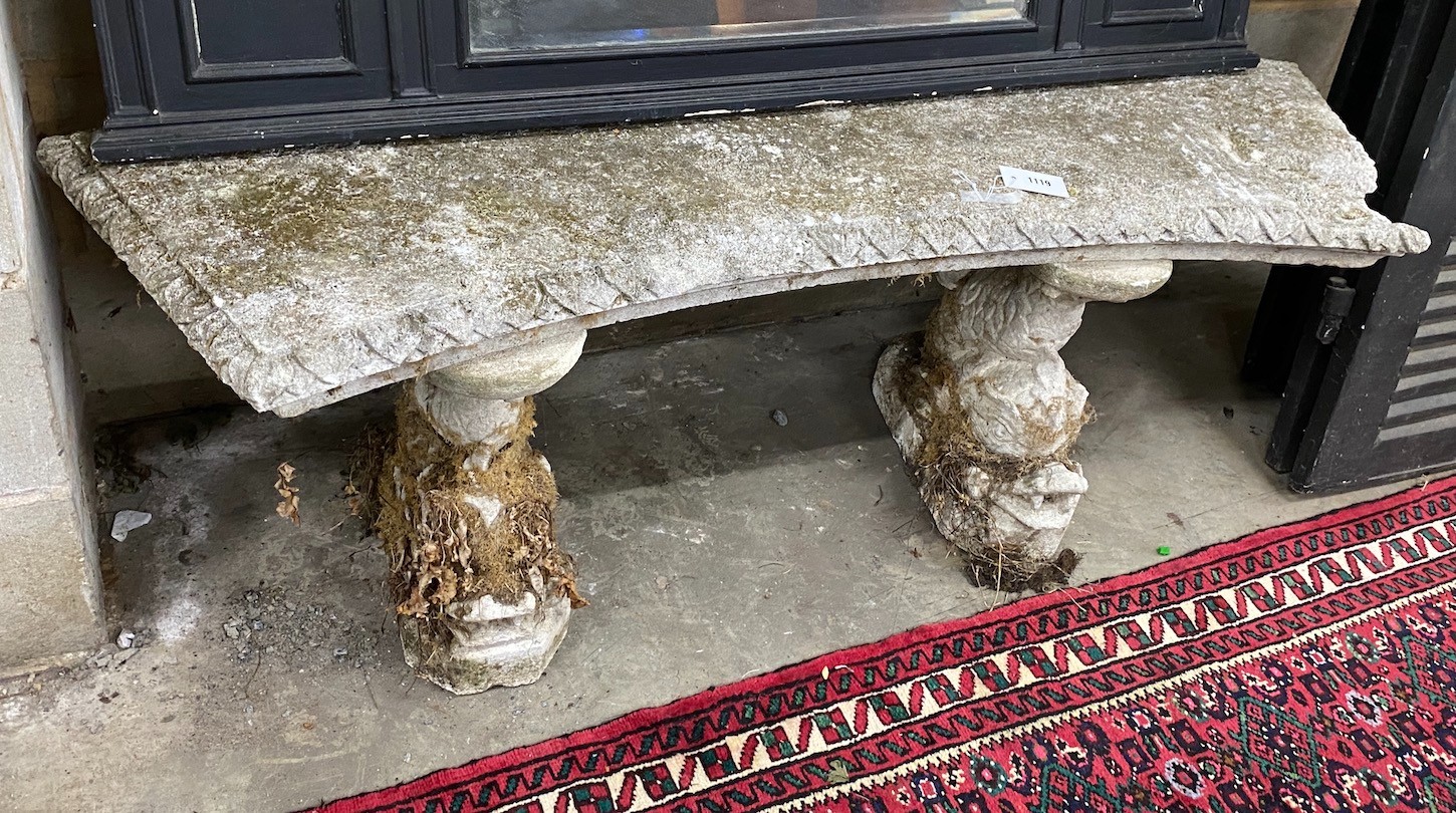 A reconstituted stone curved garden seat on dolphin supports, length 144cm, depth 33cm, height 49cm, Provenance- the late Maureen Marchioness of Dufferin and Ava, Owl House Gardens, Lamberhurst, Kent
